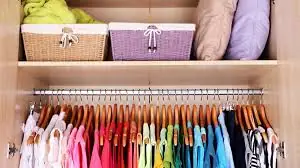 Armário com cestos, roupas de cama e cabides coloridos